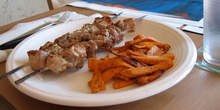 Greckie szaszłyki souvlaki z frytkami na talerzu