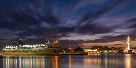 Prom Levante Ferries w porcie Zakynthos nocą, obok oświetlone nabrzeże i dzwonnica