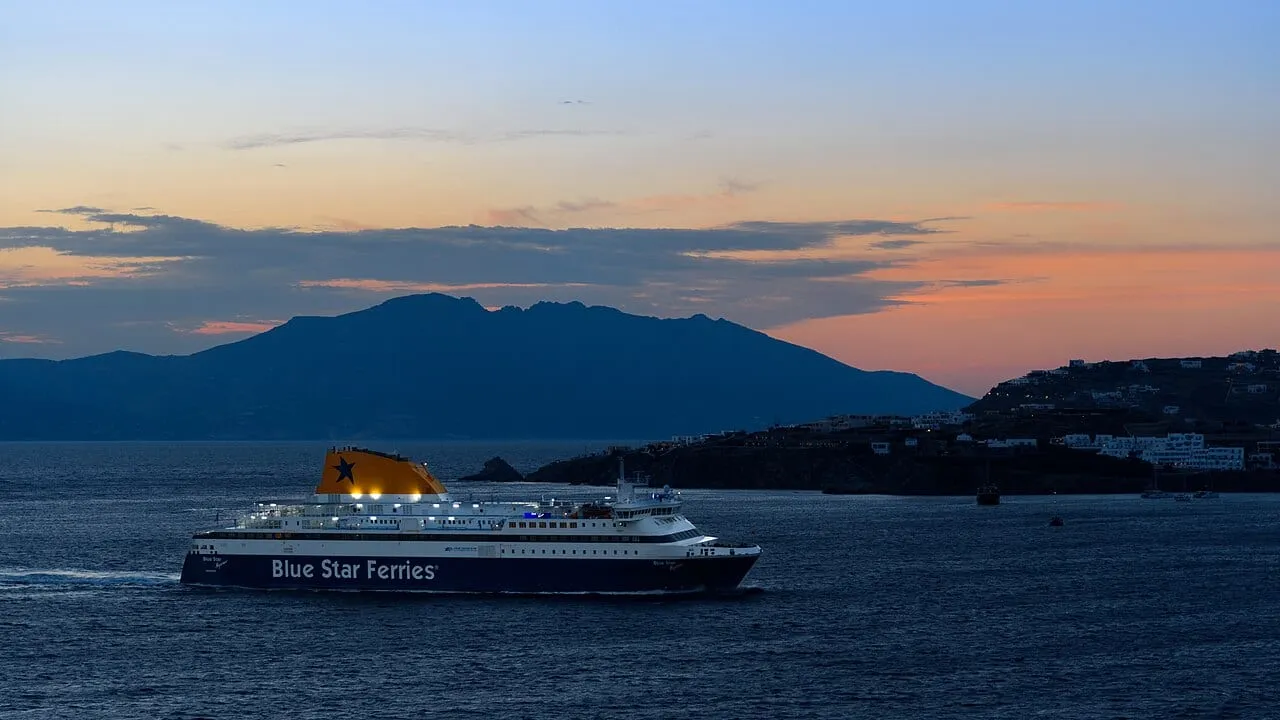 Prom wpływający do portu na Mykonos o zachodzie słońca